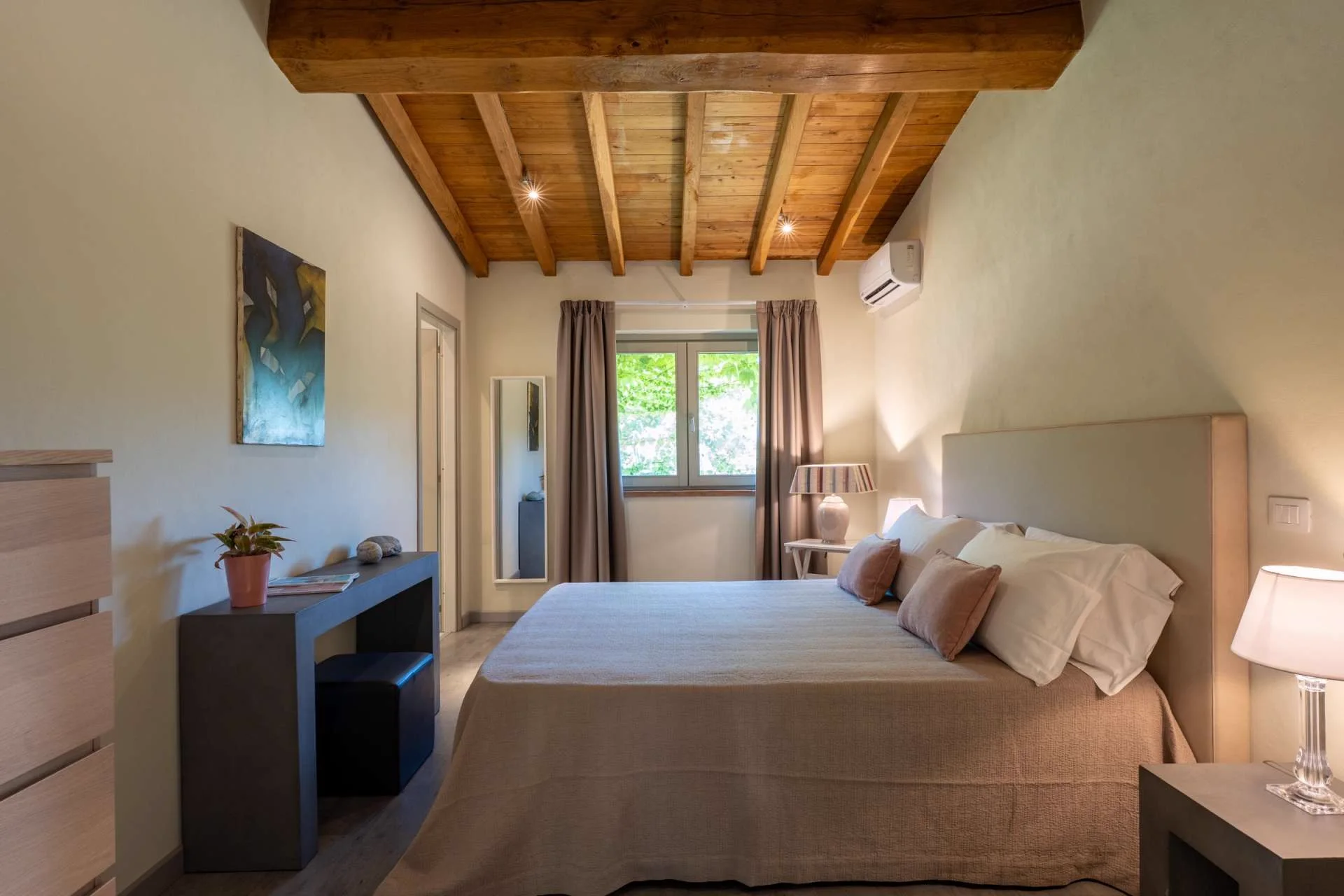A bedroom with white linen, a wooden headboard and shuttered windows.