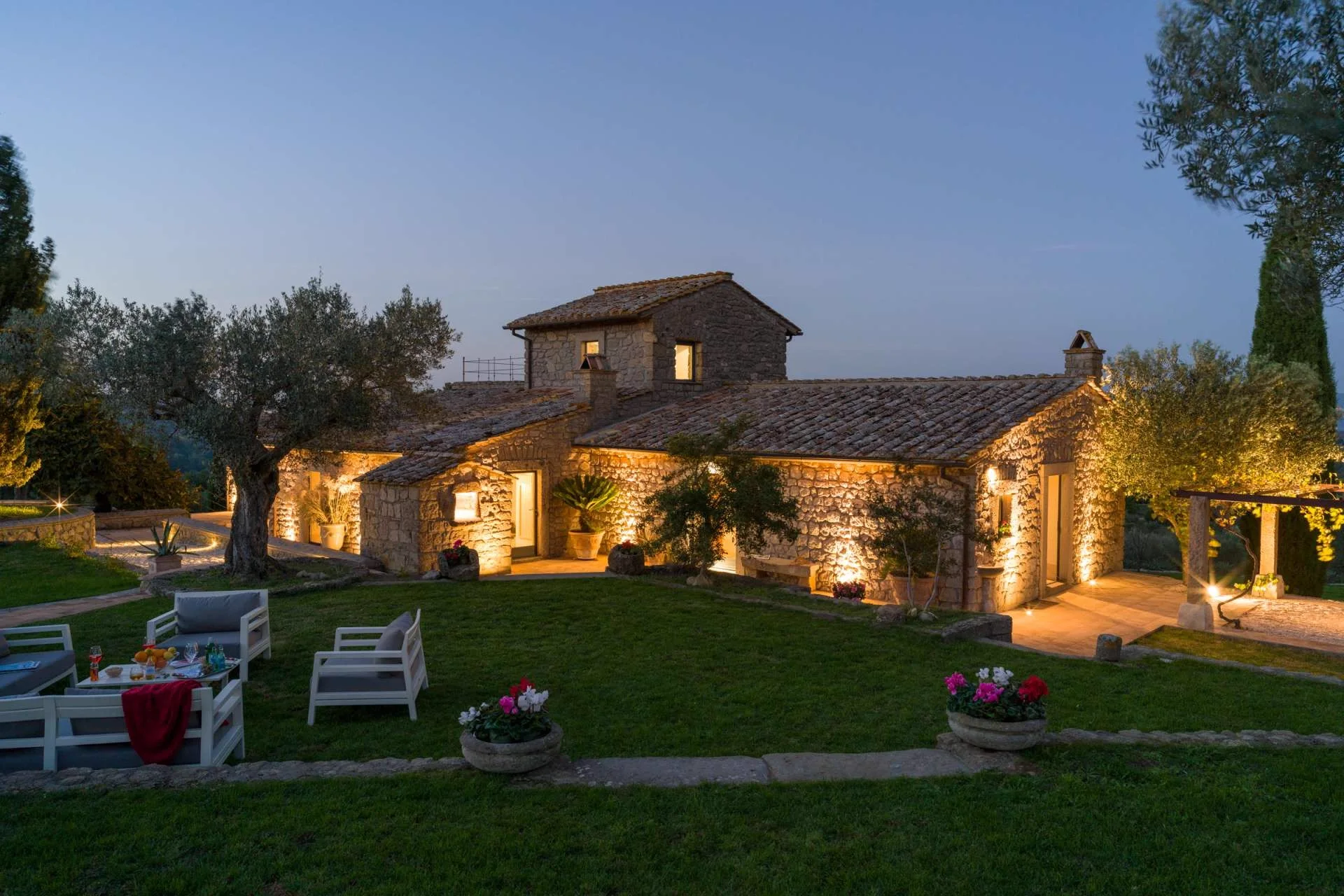 The Elaios residence at dusk, with the garden and olive trees around it.