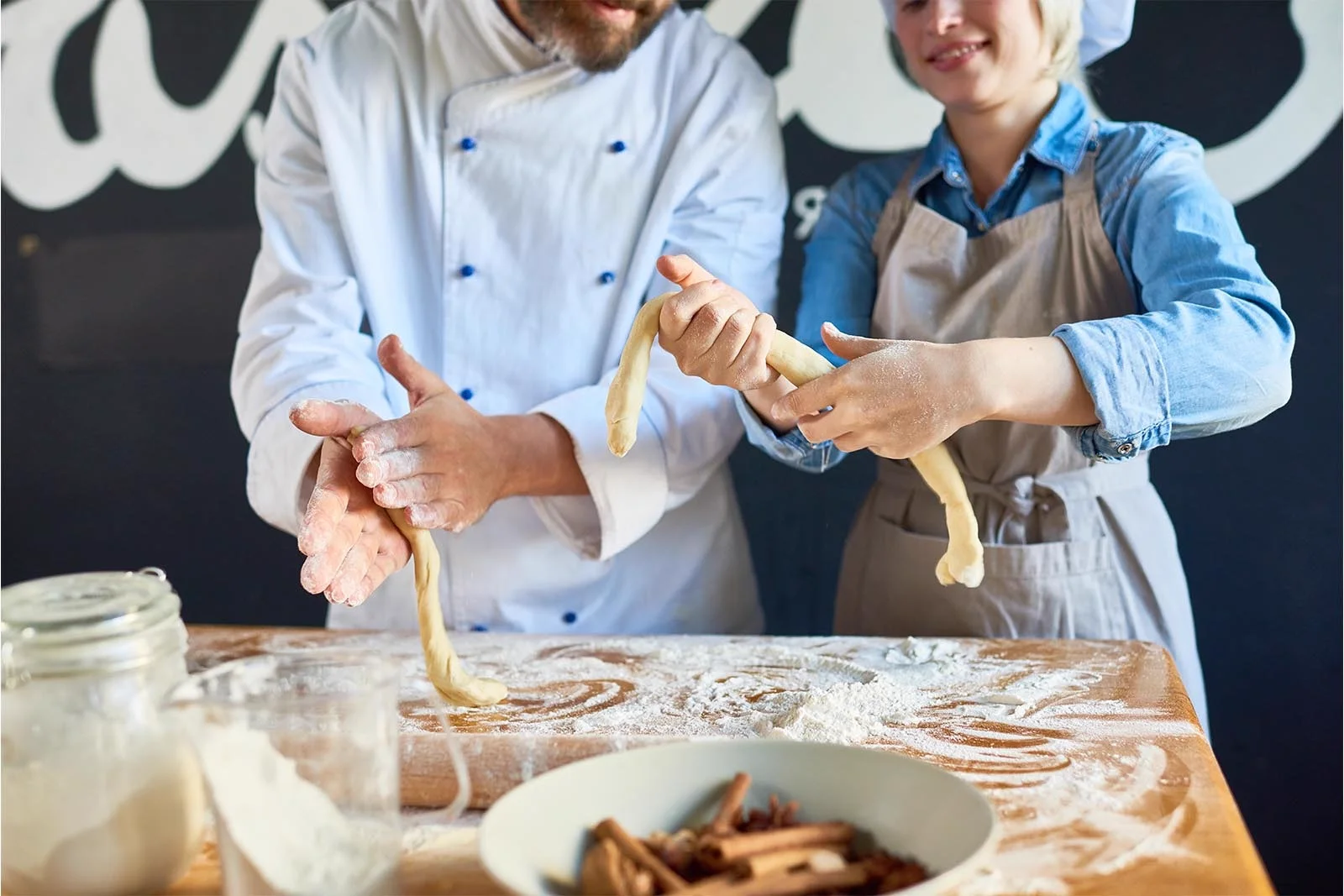 Hands shaping fresh pasta by hand on a floured wooden board.